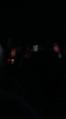 Seyirciler dramatik sahne ışıkları altında akıllı telefonlardan konser kaydediyorlar.