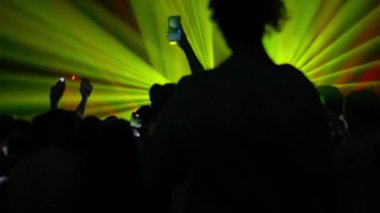 Canlı yayın sırasında yeşil, kırmızı ve mavi lazer ışıklarıyla çevrili müzik dinleyicileri