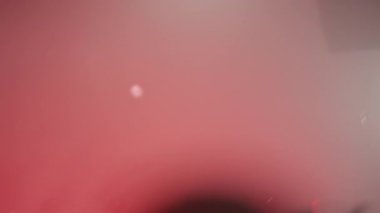 Kırmızı ışıklar altında müzisyenlerin olduğu bir sahnenin bulanık görüntüsü. Kamera sisli mekânda yankılanıyor ve elleri havada dans eden ve tezahürat yapan enerjik kalabalığı gözler önüne seriyor..