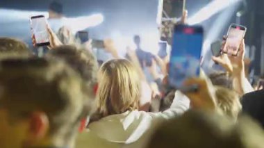 Gece bir müzik konserindeki kalabalığın görüntüsü. Taraftarlar akıllı telefonları soyup gösteriyi kaydediyorlar. Sahne, ışıklar kararmadan ve klip bitmeden önceki modern seyirci deneyimini yakalar.