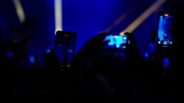 Video görüntüleri, canlı müzik konseri veya festivalinde bir hayran kitlesinin performansı kaydetmek için akıllı telefonları elinde tuttuğunu gösteriyor. Havalı mavi ve sıcak kırmızı ışık arasındaki geçiş sahnesi.