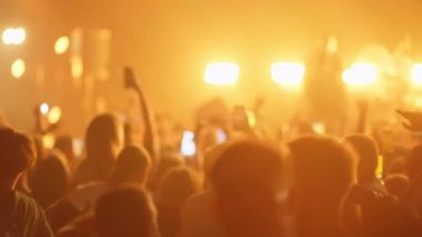 Canlı müzik konserindeki kalabalığın içinden bir video. Beyaz spot ışıklarıyla başlıyor, canlı mor sahne ışıklarına geçiyor hayranlar telefonda tezahürat yapıp kayıt yapıyor ve soluklaşıp siyaha dönüşüyor..