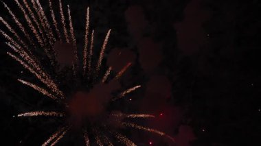 Video gece gökyüzünde patlayan parlak bir altın havai fişek yakar, kırmızı duman bulutlarına dönüşür ve sönen közlere dönüşür. Her kutlama için muhteşem bir final..