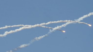 MADRID, SPAIN - 12 Ekim 2025: Birden fazla askeri uçak önlemi, parlak yanan fişekler, açık mavi gökyüzüne doğru serbest bırakıldı. Isı güdümlü füzeler için yem olarak uzun, kavisli beyaz duman izleri bırakırlar..