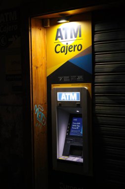 VALENCIA, İspanya - 6 Şubat 2026: Açık hava nakit dağıtım istasyonu, açık sarı ATM Cajero tabelası ve akşam saatlerinde ücretsiz seyahat eSIM hizmetleri ekran reklamı