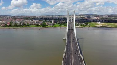 Portekiz, Lizbon 'daki Vasco da Gama Köprüsü boyunca ilerleyen hava aracı görüntüleri. Güneşli bir günde Tagus Nehri 'ni geçerken arka planda şehrin ufuk çizgisini gösterir.