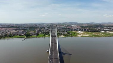 Lizbon, Portekiz 'deki görkemli Vasco da Gama Köprüsü boyunca ilerleyen hava aracı videosu Tagus Nehri üzerinde modern mimari, trafik akışı ve şehir manzarasını gözler önüne seriyor.