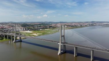 Portekiz, Lizbon 'daki Tagus Nehri üzerindeki Vasco da Gama Köprüsü' nün insansız hava aracı görüntüsü. Güneşli bir günde arka planda şehir manzarası olan modern otoyolda arabalar sürüyor.