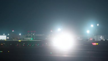 Havaalanı pistinde taksicilik yapan ve kameraya yaklaşan bir uçağın dinamik gece videosu.