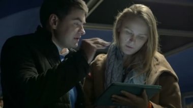 Düz yürüyen merdivende tablet bilgisayar kullanan çift