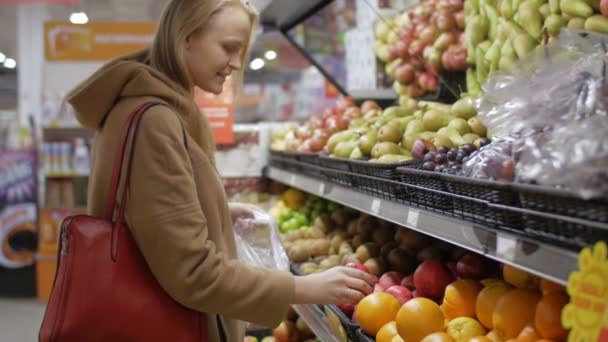 Jovem mulher escolhendo frutas frescas no supermercado — Vídeo de Stock