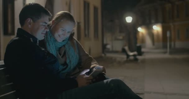 Молода пара використовує майданчик на вуличній лавці — стокове відео