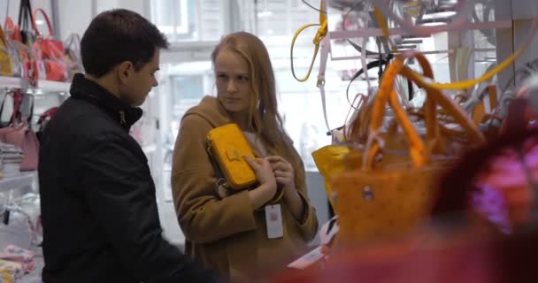 Семейная пара покупает дамскую сумочку в магазине — стоковое видео
