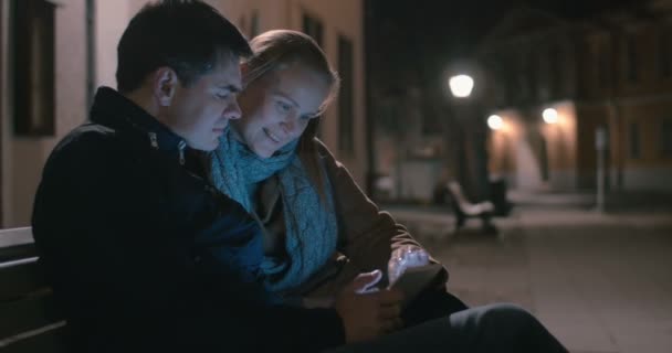 Пара сидящих на скамейке с планшетом — стоковое видео