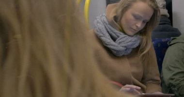 Young woman using tablet computer in subway train