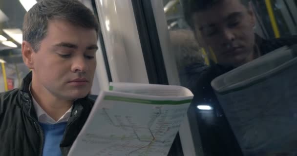 Человек с газетой путешествует на поезде метро — стоковое видео