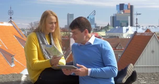 Hombre y mujer usando almohadilla y mapa en la ciudad — Vídeo de stock