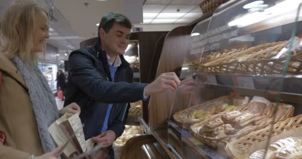 Hombre y mujer comprando delicioso bollo en la tienda — Vídeos de Stock