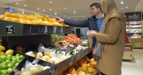 Pareja feliz eligiendo naranjas en supermercado — Vídeos de Stock