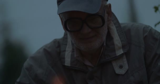 Aged man thinking and keeping an eye to the fire — Stock Video