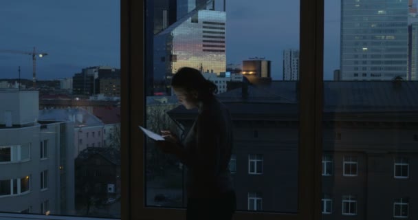 Жінка вводить планшет біля вікна — стокове відео