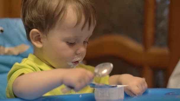 Kleine jongen in kinderstoel met lepel — Stockvideo