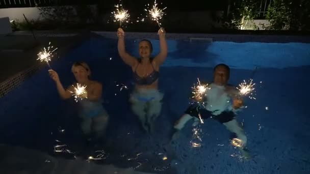 Familia o amigos con luces de Bengala en la piscina — Vídeo de stock