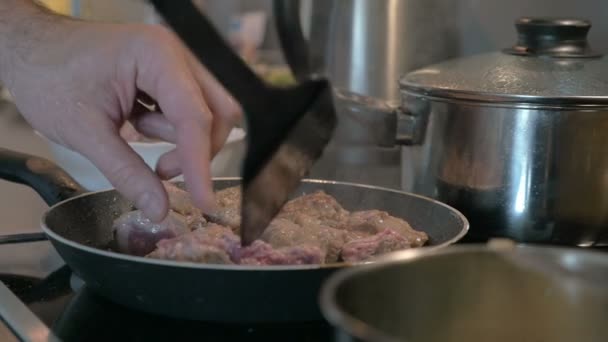 Человек, превращающий мясо в сковороде — стоковое видео