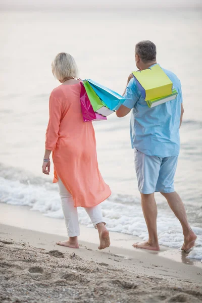 Couple walking on the beach after vacation shopping — Stock Photo, Image