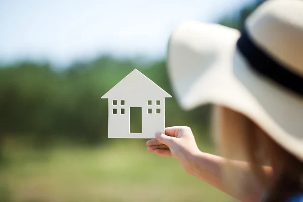 Woman holding house model in the countryside — Stockfoto