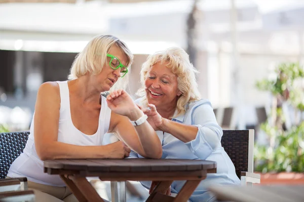 Las mujeres maduras usando reloj inteligente en la cafetería de la calle — Foto de Stock