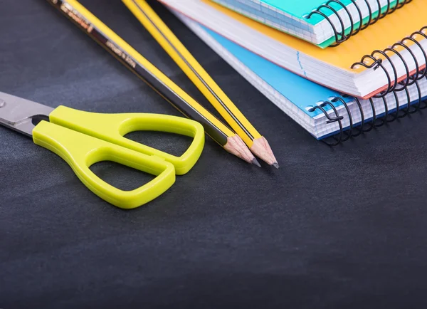 Tijeras de útiles escolares, cuadernos lápices sobre un fondo oscuro —  Fotos de Stock