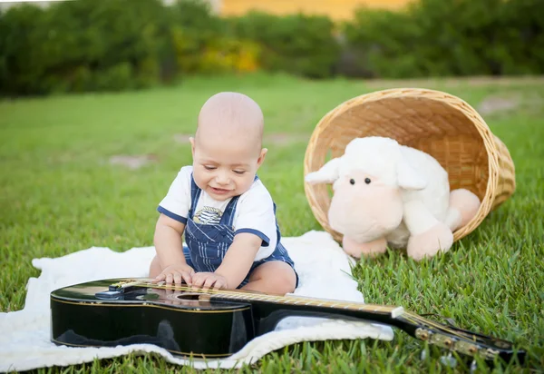 Liten pojke med en gitarr på gräset — Stockfoto
