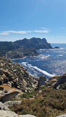 Kıyı manzarası dramatik uçurumlar, parlak okyanus dalgaları ve parlak bir gökyüzü altındaki zengin bitki örtüsü huzur ve doğal güzelliği çağrıştırıyor.
