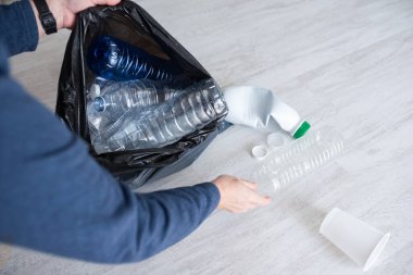 Eller siyah torbalarda plastik şişeleri topluyor, ev atıkları sınıflandırılıyor, sürdürülebilirlik yaşam tarzı reklamları yapılıyor..