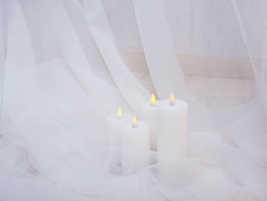 Beyaz elektrikli mumlar, yumuşak beyaz tül kumaş içinde parıldıyor. Düğün dekorasyonu ya da kaplıca salonu reklamı için..