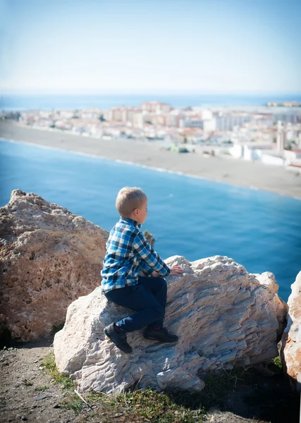 Kayaların üzerinde oturan küçük çocuk — Stok fotoğraf