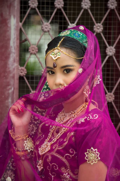 肖像画アジアの女性は マルジェンタインドの伝統的なサリで 彼女は錬鉄製のドアの側を見下ろしています — ストック写真