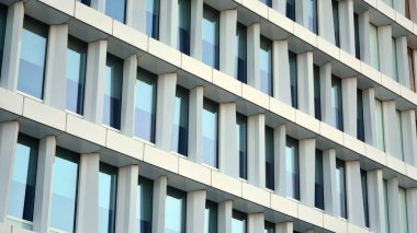 Mavi gökyüzünün altındaki tonlu cam ve çelik yapılardan yapılmış mavi perde duvarı. Bir binanın parçası..