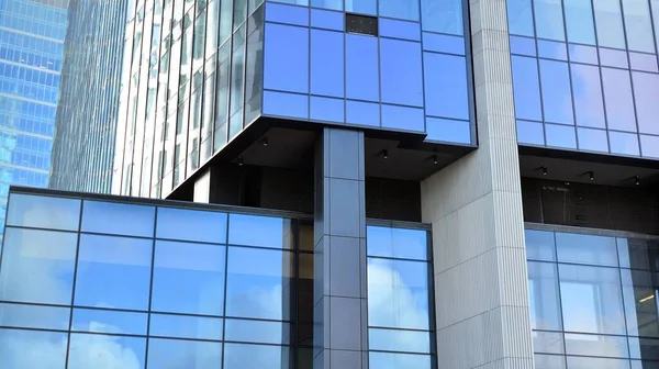 Blue curtain wall made of toned glass and steel constructions under blue sky. A fragment of a building.