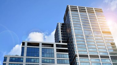 İş bölgesindeki modern ofis binalarının alt manzarası. Gökdelen cam cepheleri masmavi gökyüzünde güneş ışınlarıyla aydınlık bir günde.