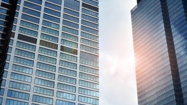 Mavi gökyüzünün altındaki tonlu cam ve çelik yapılardan yapılmış mavi perde duvarı. Binanın bir parçası. Parlak güneşli bir günde mavi gökyüzünde güneş ışınlarıyla cam cepheler..