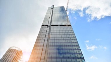 İş bölgesindeki modern ofis binalarının alt manzarası. Gökdelen cam cepheleri masmavi gökyüzünde güneş ışınlarıyla aydınlık bir günde.