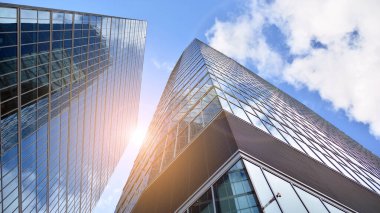 İş bölgesindeki modern ofis binalarının alt manzarası. Gökdelen cam cepheleri masmavi gökyüzünde güneş ışınlarıyla aydınlık bir günde.