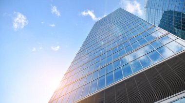 İş bölgesindeki modern ofis binalarının alt manzarası. Gökdelen cam cepheleri masmavi gökyüzünde güneş ışınlarıyla aydınlık bir günde.