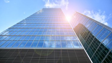 İş bölgesindeki modern ofis binalarının alt manzarası. Gökdelen cam cepheleri masmavi gökyüzünde güneş ışınlarıyla aydınlık bir günde.