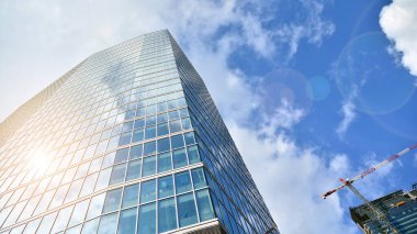 İş bölgesindeki modern ofis binalarının alt manzarası. Gökdelen cam cepheleri masmavi gökyüzünde güneş ışınlarıyla aydınlık bir günde.