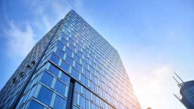 Mavi gökyüzünün altındaki tonlu cam ve çelik yapılardan yapılmış mavi perde duvarı. Binanın bir parçası. Parlak güneşli bir günde mavi gökyüzünde güneş ışınlarıyla cam cepheler..