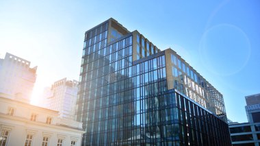 Mavi gökyüzünün altındaki tonlu cam ve çelik yapılardan yapılmış mavi perde duvarı. Binanın bir parçası. Parlak güneşli bir günde mavi gökyüzünde güneş ışınlarıyla cam cepheler..