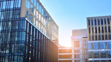 Mavi gökyüzünün altındaki tonlu cam ve çelik yapılardan yapılmış mavi perde duvarı. Binanın bir parçası. Parlak güneşli bir günde mavi gökyüzünde güneş ışınlarıyla cam cepheler..